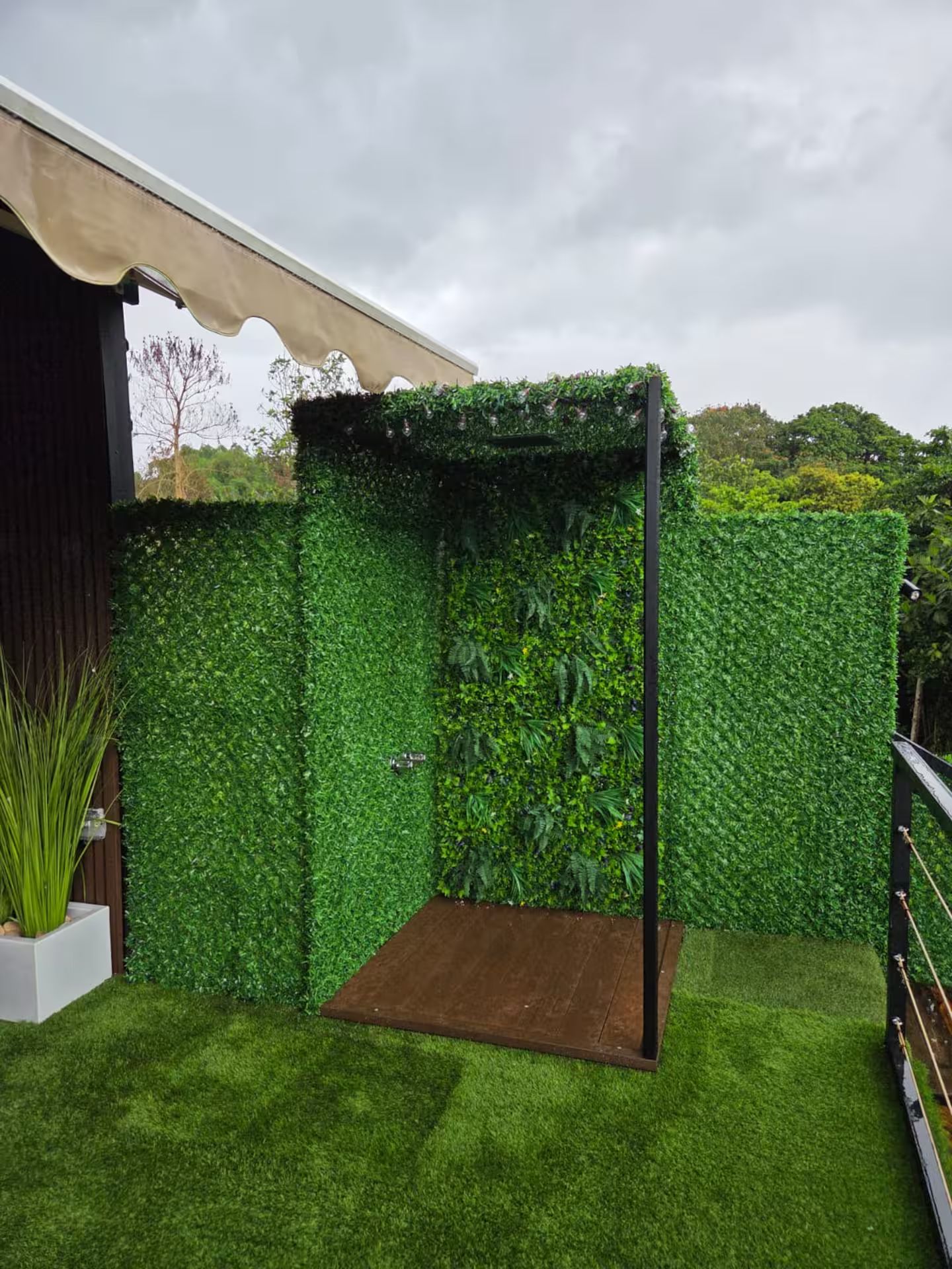 Un jardin avec un banc en bois, un pot de fleurs blanc et une pergola recouverte de verdure.