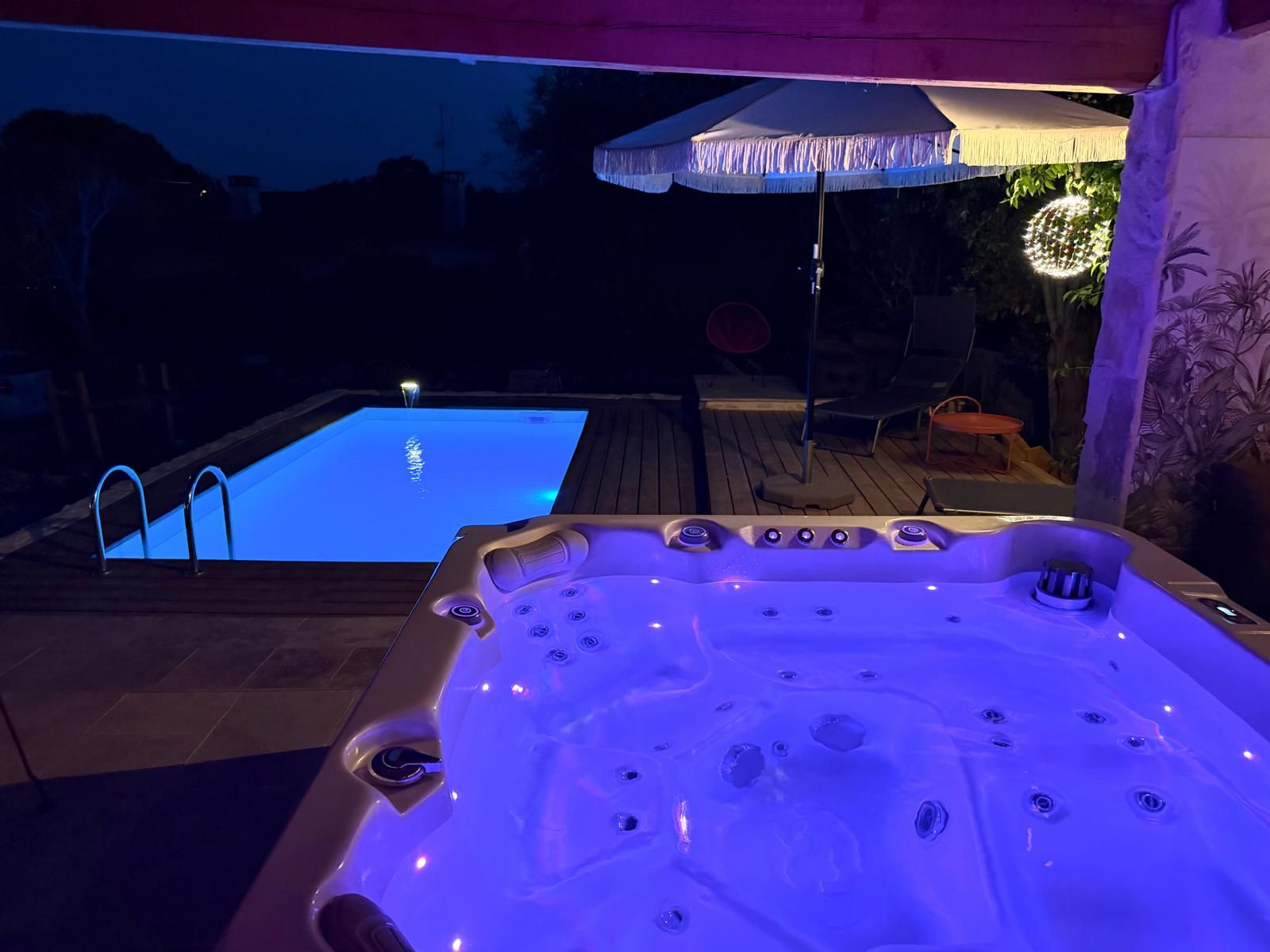 Een bubbelbad met bedieningspaneel en een zwembad met een trap.