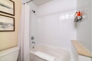 A bathroom with a bathtub, a shower, and a towel rack. - Sleek Studio in Fort York Near Lake & Liberty (Toronto)
