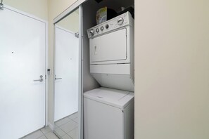 A laundry room with a white washing machine, a dryer, and a door. - Sleek Studio in Fort York Near Lake & Liberty (Toronto)