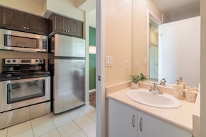 A kitchen with a microwave, oven, and refrigerator. - Sleek Studio in Fort York Near Lake & Liberty (Toronto)