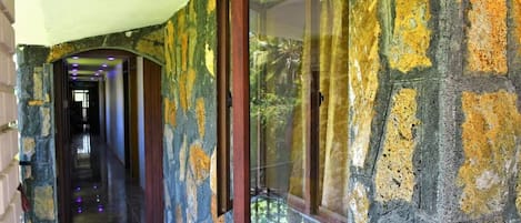 A stone corridor with a wooden-framed window and a door leading to another room.