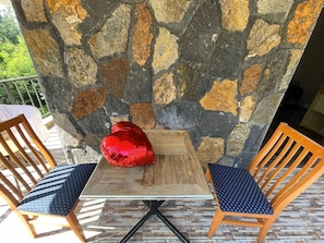 Una mesa con dos sillas, un adorno rojo y una pared de piedra.