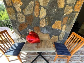 Una mesa con dos sillas, un adorno rojo y una pared de piedra.