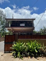 Un edificio de dos pisos con un balcón, un letrero y una entrada con portones.