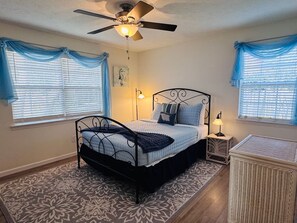 A bedroom with a bed, a ceiling fan, a nightstand, and a bedside table. - Coastal Hangout | Hot Tub | GameRm | Mins2Bch (Panama City)