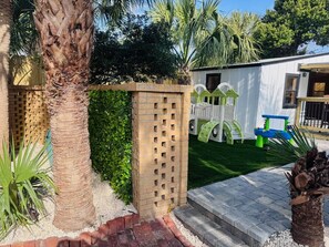 A residential area with a brick wall, a palm tree, and a white building with a window. - One-Block Beach Oasis w/ Poolside Game & Golf Cart (Panama City Beach)