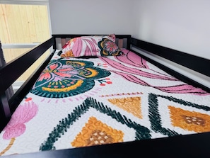 A bed with a colorful quilt and a wooden headboard. - One-Block Beach Oasis w/ Poolside Game & Golf Cart (Panama City Beach)