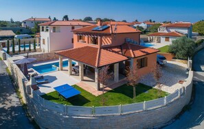 Propiedad residencial con piscina, zona de estar exterior y patio cubierto.