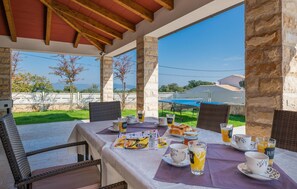 An outdoor dining area with stone pillars, wicker chairs, and a table set for breakfast. - Lovely home in Kavran with private swimming pool, can be inside or outside (Kavran)