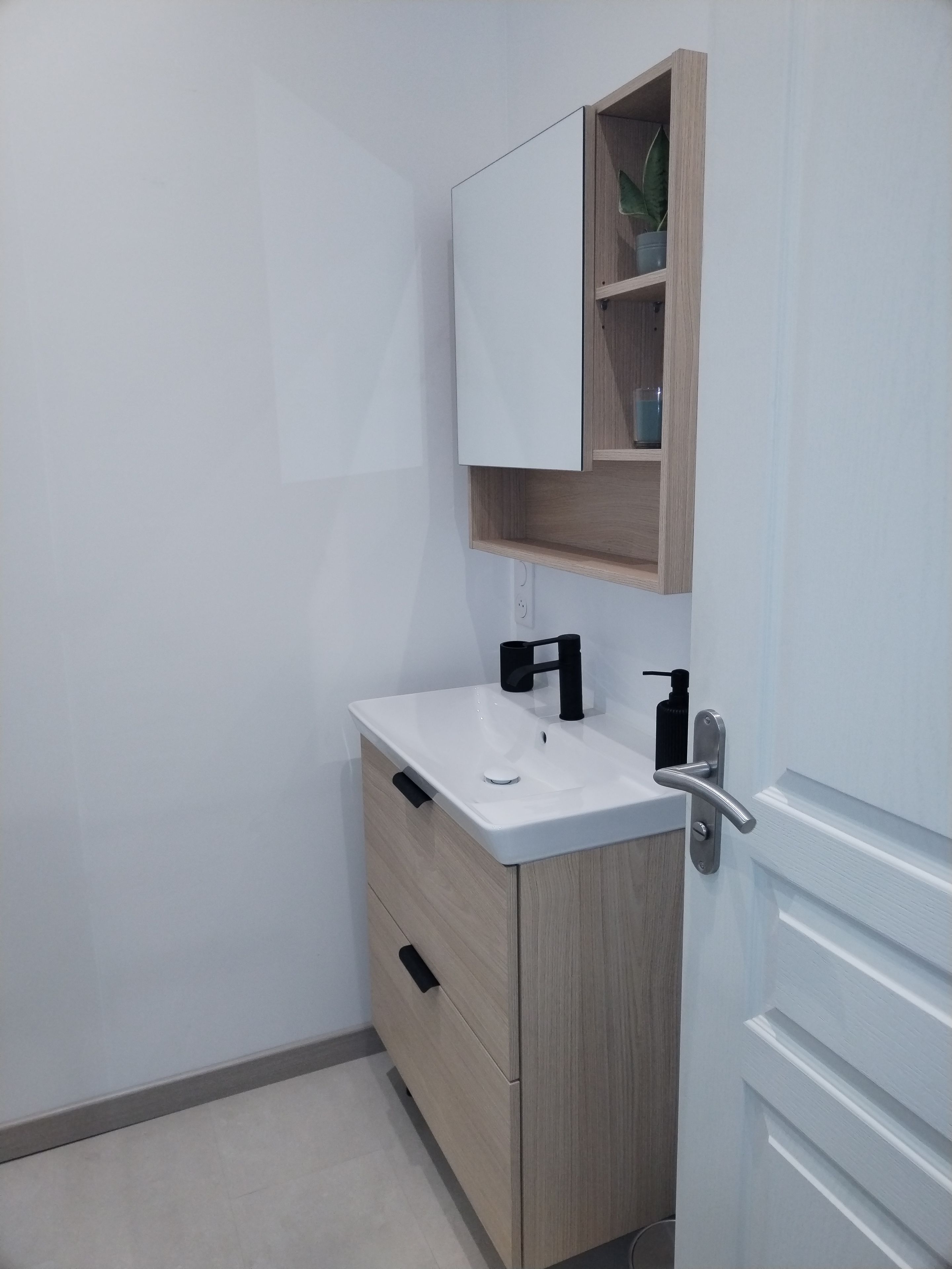 Ein Badezimmer mit einem weißen Waschbecken, einem Holzschrank und einem Spiegel darüber.