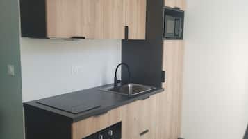 A modern kitchen with wooden cabinets, a black countertop, a built-in microwave, and a black oven.