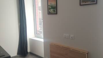 Ein Zimmer mit Heizkörper, einem Fenster mit Blick und einem Bild an der Wand.