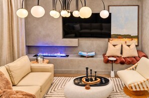 A modern living room with a fireplace, a mounted TV, and a comfortable seating area. - Nash Lux - Pool/Hot tub - 11 beds - Game Room! (Nashville)