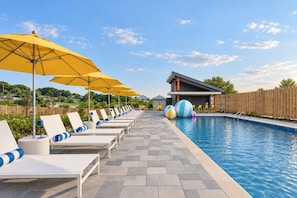 Un espace piscine avec des chaises longues et des parasols.
