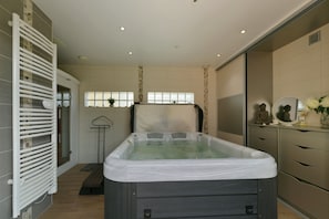 Ein modernes Badezimmer mit Whirlpool, Dusche und Waschtisch mit Spiegel und Dekoration.