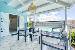A covered outdoor seating area with a pool in the background. - Villa Rosalie - Piscine - Proche plage (Le Diamant)