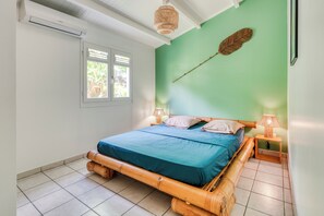 A room with a bed, a window, a wall-mounted lamp, and a wall decoration. - Villa Rosalie - Piscine - Proche plage (Le Diamant)