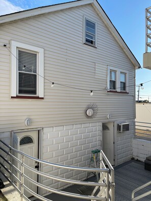 A two-story house with a garage door, a small window with blinds, and a decorative sun on the wall. - Admiral's Suite 300ft to Beach and Boardwalk (Seaside Heights)