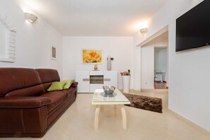 A living room with a brown leather sofa, a glass coffee table, a white cabinet, and a painting on the wall. - Casa St. Domenica your peaceful holiday retreat (Vrećari)