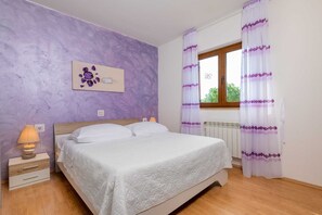 A bedroom with a bed, a nightstand, a wall-mounted artwork, a window with curtains, and a radiator. - Casa St. Domenica your peaceful holiday retreat (Vrećari)