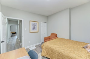 A bedroom with a bed, a chair, a desk, and a door leading to another room. - The Euclid House Stylish 6BR By UChicago, Obama Presidential Center & Lakefront (Chicago)