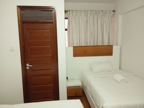 A room with a wooden door, a bed with a white mattress and pillows, a small bedside table, and a window with curtains. - Sleek and stunning 2 bedroom to let in kilimani, walking distance to yaya center (Nairobi)