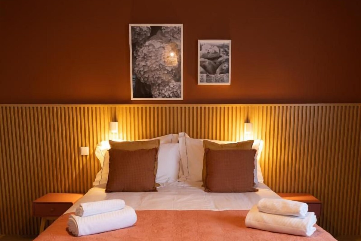 A hotel room with a large bed, two bedside tables, and wall-mounted lamps.