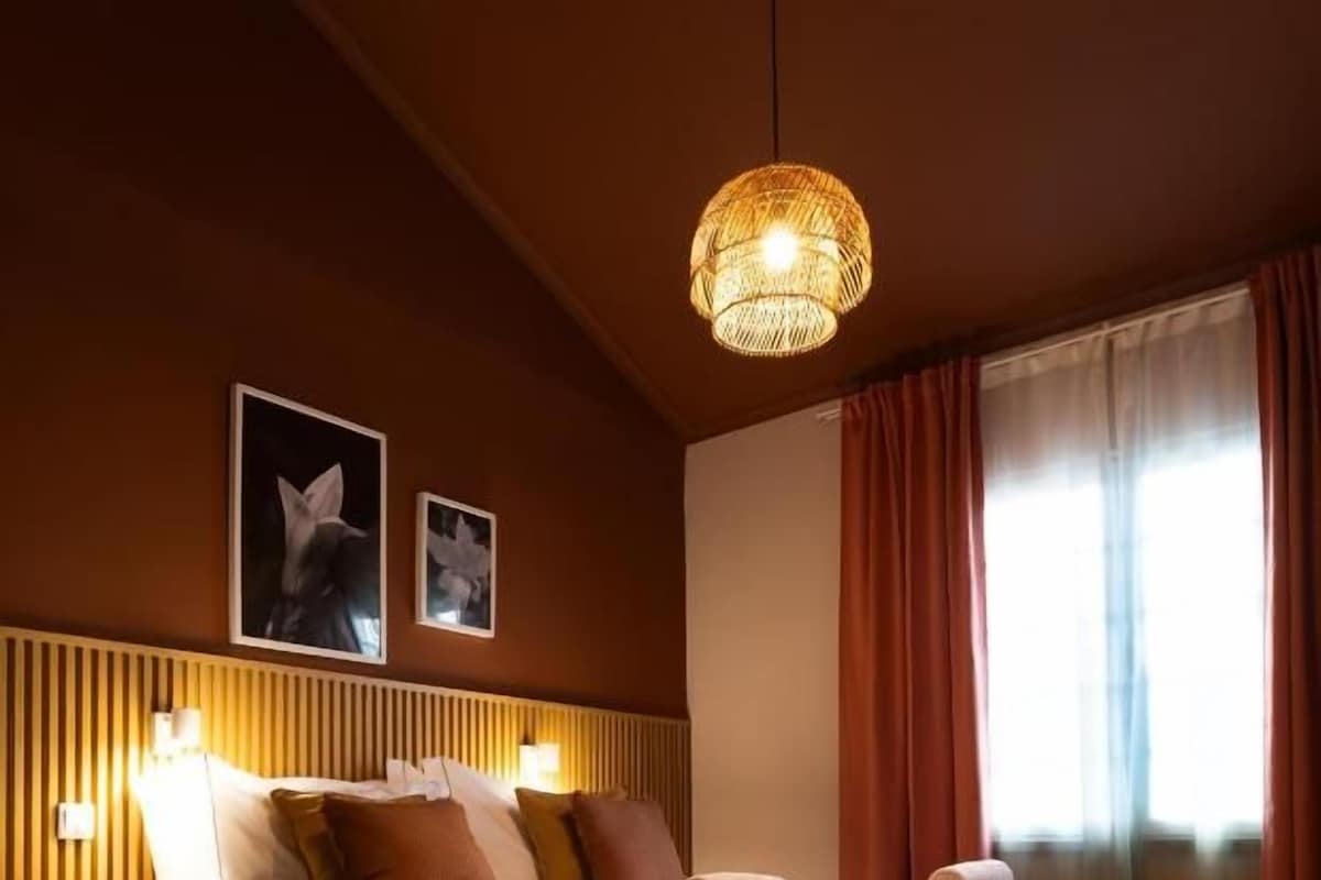 Ein ordentlich bezogenes Bett mit Kissen und Decke, eine Nachttischlampe und ein gerahmtes Bild an der Wand.