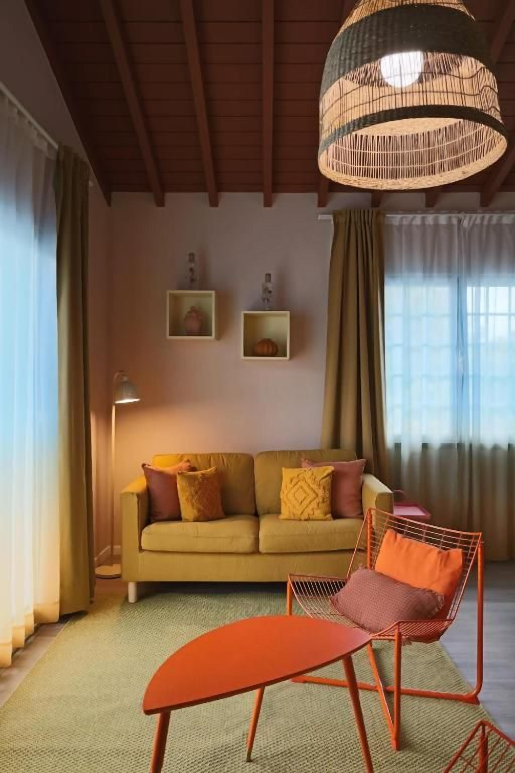 Sala de estar com sofá, poltrona, luminária de chão e pendente.