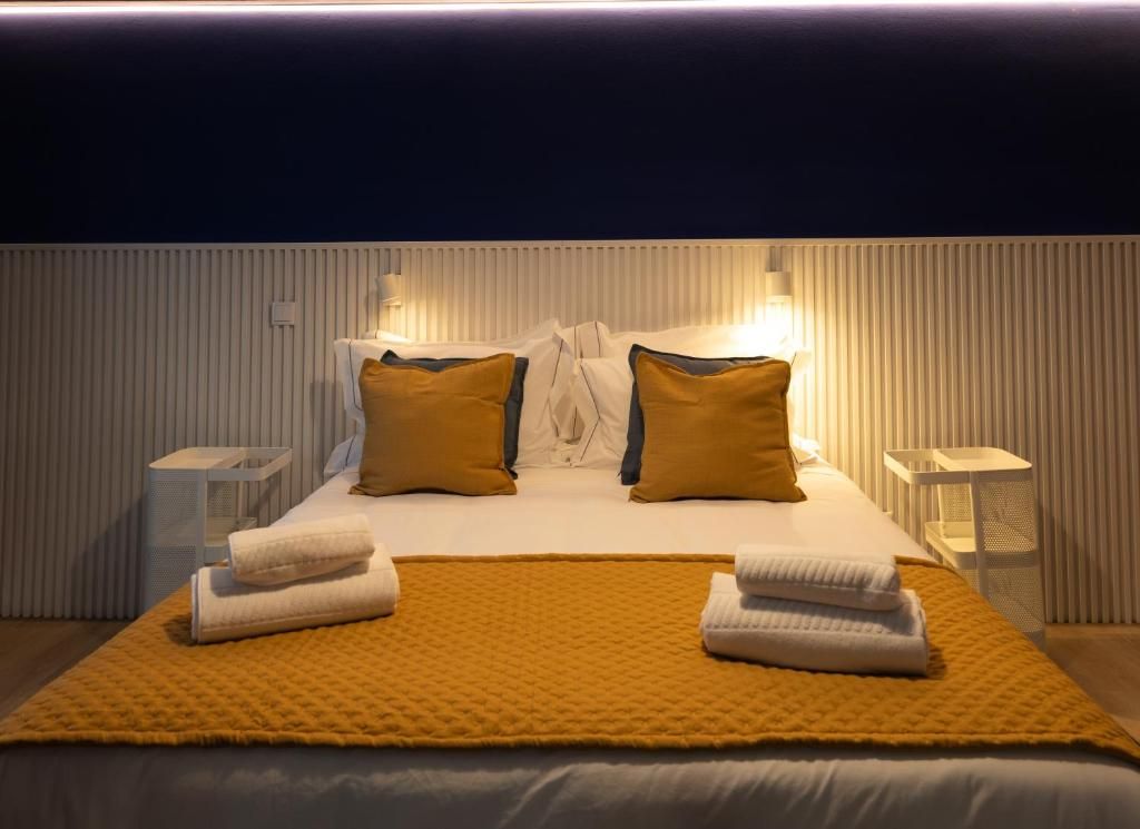 A hotel room with a bed, two bedside tables, and a headboard with integrated lighting.
