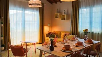 Comedor con una mesa dispuesta para cuatro personas, rodeada de sillas, bajo un techo de madera con vigas a la vista.