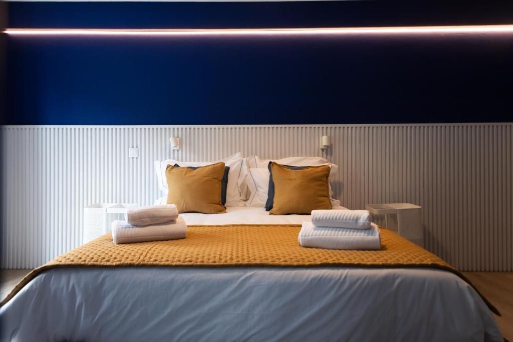 A hotel room with a bed, pillows, a bedside table, and a lamp.