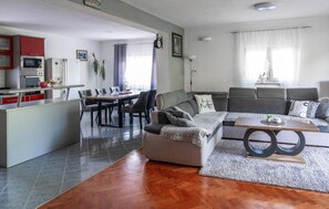 A modern living space with a dining area, a sofa set, and a kitchen with red cabinets. - Amazing home in Zmijavci with private swimming pool, can be inside or outside (Zmijavci)
