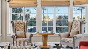 A room with two patterned armchairs, a chessboard, and a round table with drinks. - Palm Manor by Avantstay Historic Home + Private Pool Pergola Dining + Lawn Mins to Downtown (Phoenix)