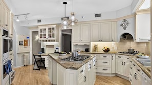 A modern kitchen with white cabinetry, a central island, and a built-in oven. - Palm Manor by Avantstay Historic Home + Private Pool Pergola Dining + Lawn Mins to Downtown (Phoenix)