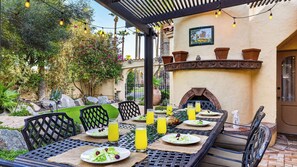 An outdoor dining area with a pergola, tables, chairs, and a fire pit. - Palm Manor by Avantstay Historic Home + Private Pool Pergola Dining + Lawn Mins to Downtown (Phoenix)