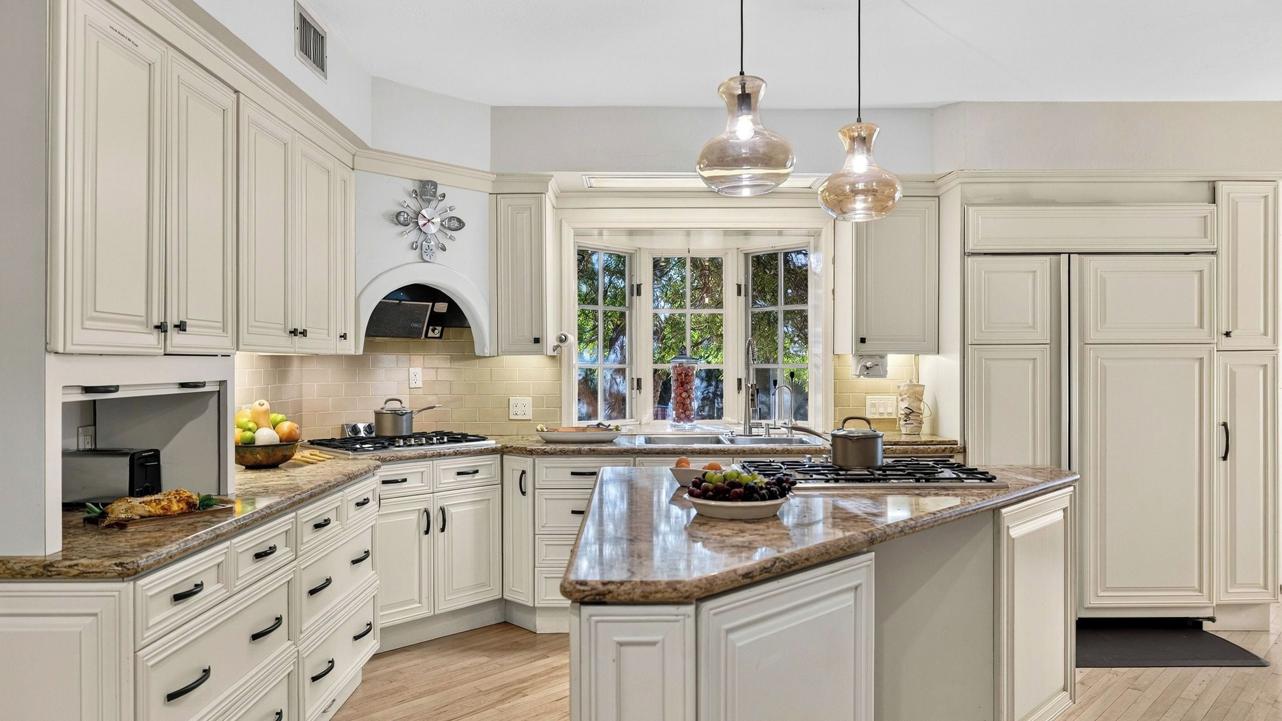 A spacious kitchen with white cabinetry, a large island, and a built-in oven.