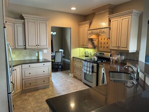 A kitchen with light-colored cabinets, a stainless steel refrigerator, a stove, and a sink.