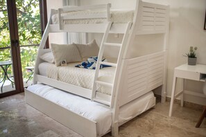 Een stapelbed met een ladder, een tafeltje met een bloempot, en uitzicht op groen buiten.