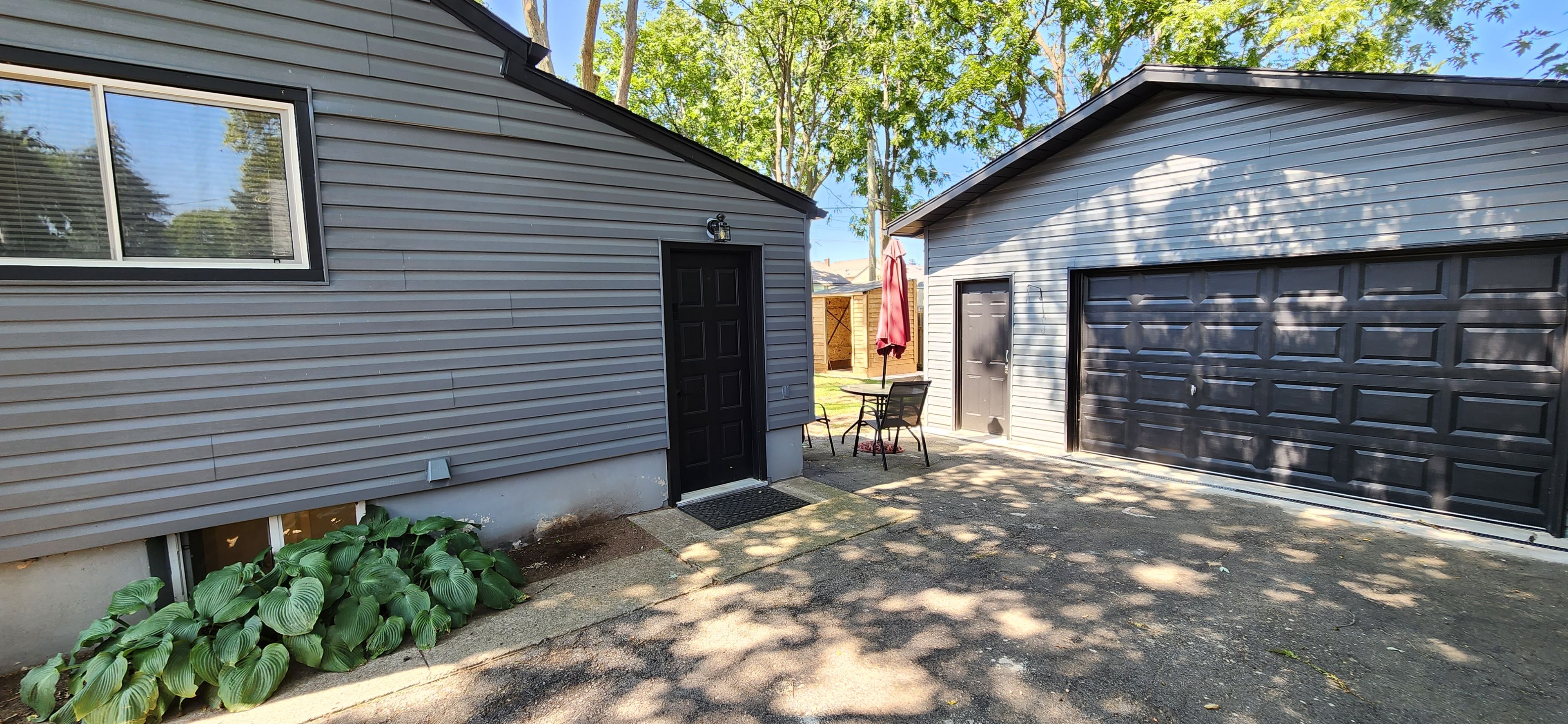 A residential garage with a black door and a garage door.