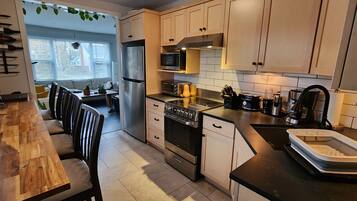 A modern kitchen with a wooden dining table, built-in appliances, and a view to a dining area.