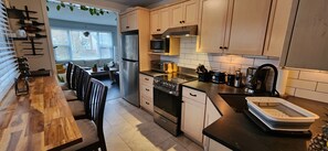 Eine moderne Küche mit Holztisch, integrierten Geräten und Blick in einen Essbereich.