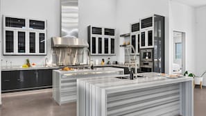 A modern kitchen with a central island, stainless steel appliances, and black cabinets. - Exeter House by Avantstay Sleeps 18 + Casita Pool + Spa + Theater Camelback Views (Phoenix)