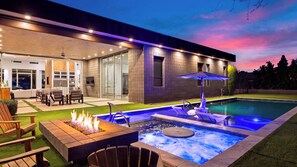 Ein moderner Poolbereich im Freien mit Whirlpool, Sitzgelegenheiten und einer Feuerstelle.