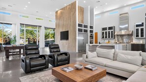 A modern living room with leather chairs, a sofa, a coffee table, and a kitchen area with a stainless steel range hood. - Exeter House by Avantstay Sleeps 18 + Casita Pool + Spa + Theater Camelback Views (Phoenix)