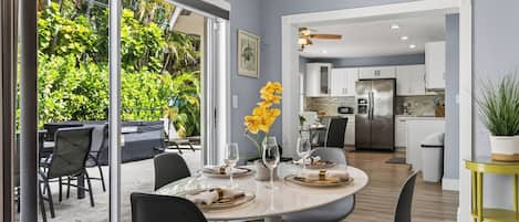 A modern dining area with a glass table, chairs, and a vase of yellow flowers.