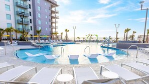 A pool area with multiple pools, sun loungers, and a building with balconies. - Spacious 2BR Villa at Myrtle Beach Oceanfront – Full Kitchen & Resort Fun (Myrtle Beach)