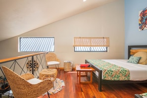 A cozy room with a bed, a chair, a small table, and two windows. - Aloki Wim 4 – A pasos de la Playa (Playa Chiquita)