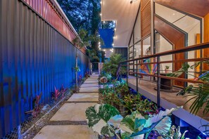 A narrow pathway flanked by a blue wall and a wooden structure with glass windows. - Aloki Wim 4 – A pasos de la Playa (Playa Chiquita)